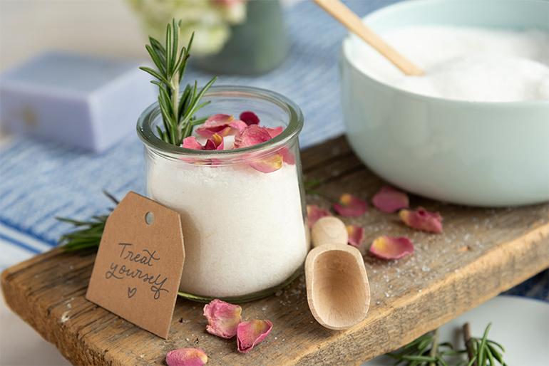 Salt in a Oui by Yoplait yogurt jar with a bowl of salt next to it as well as some fresh herbs.